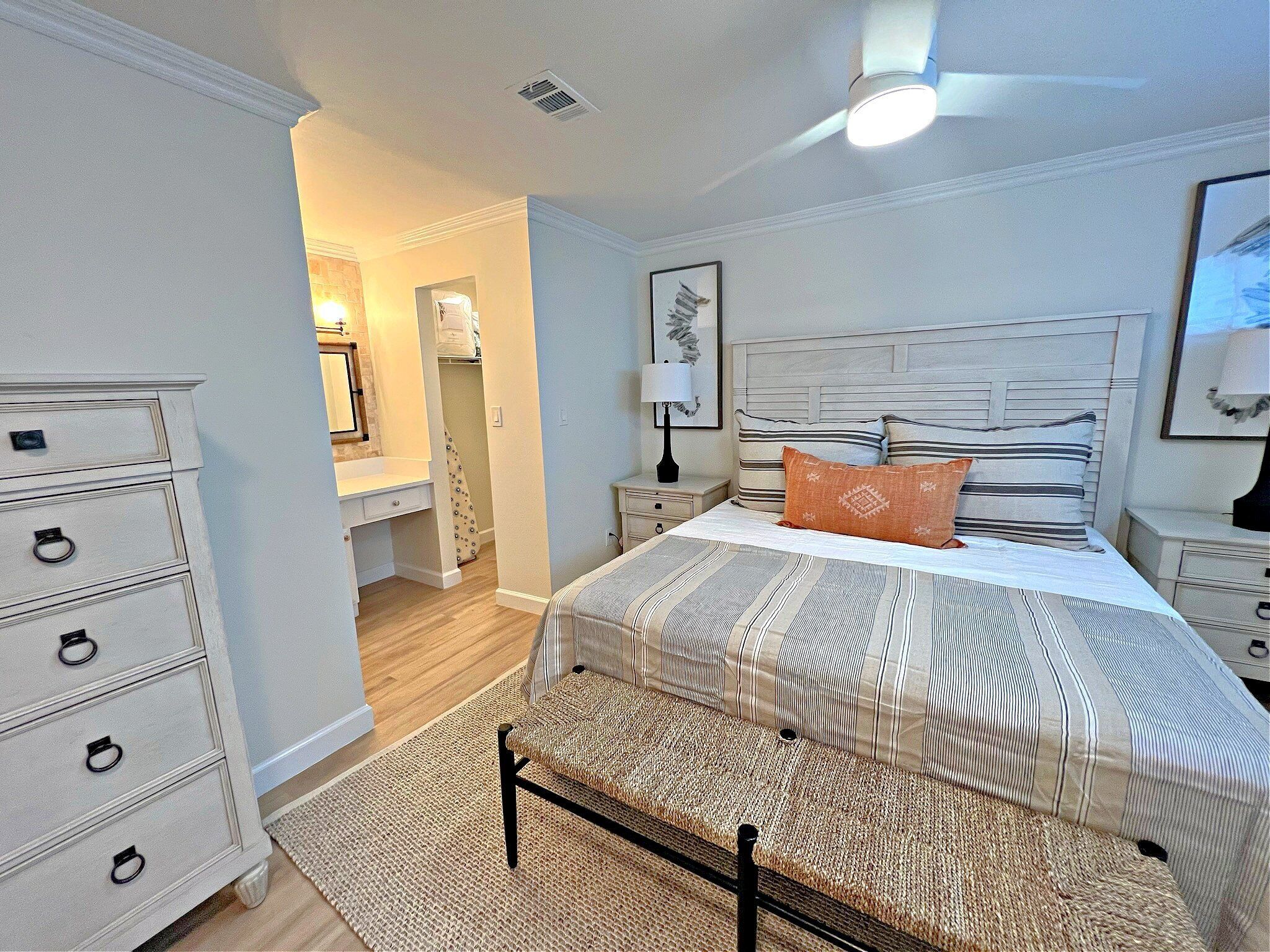 A bedroom with a bed, nightstands, a dresser, and a walk-in closet.