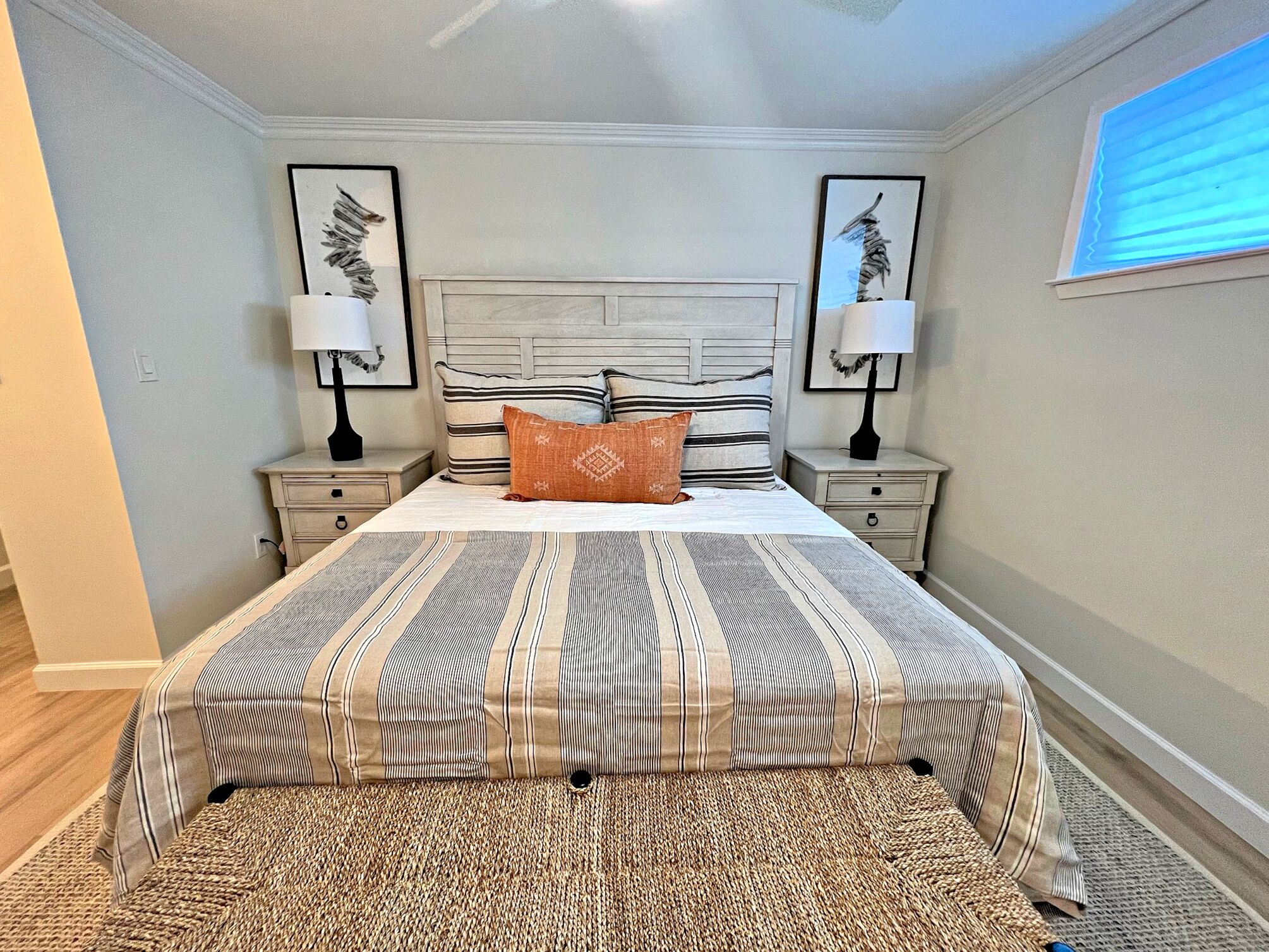 A bedroom with a bed, two nightstands, two lamps, and two framed pictures on the wall.