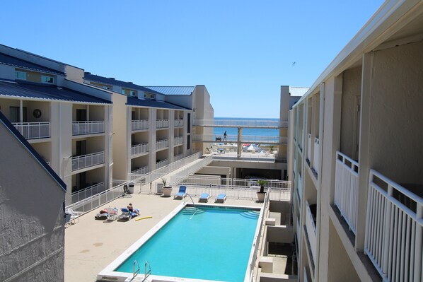 Un espace piscine doté de plusieurs niveaux de balcons, offrant une vue dégagée sur la mer, et comprenant un espace salon abrité.