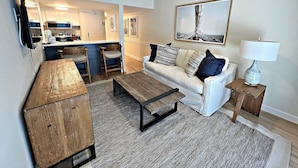 A modern living room with a sofa, coffee table, and a TV mounted on the wall. - Sugar Beach (Orange Beach)