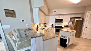 A modern kitchen with white cabinetry, a granite countertop, and stainless steel appliances. - Summerhouse (Orange Beach)