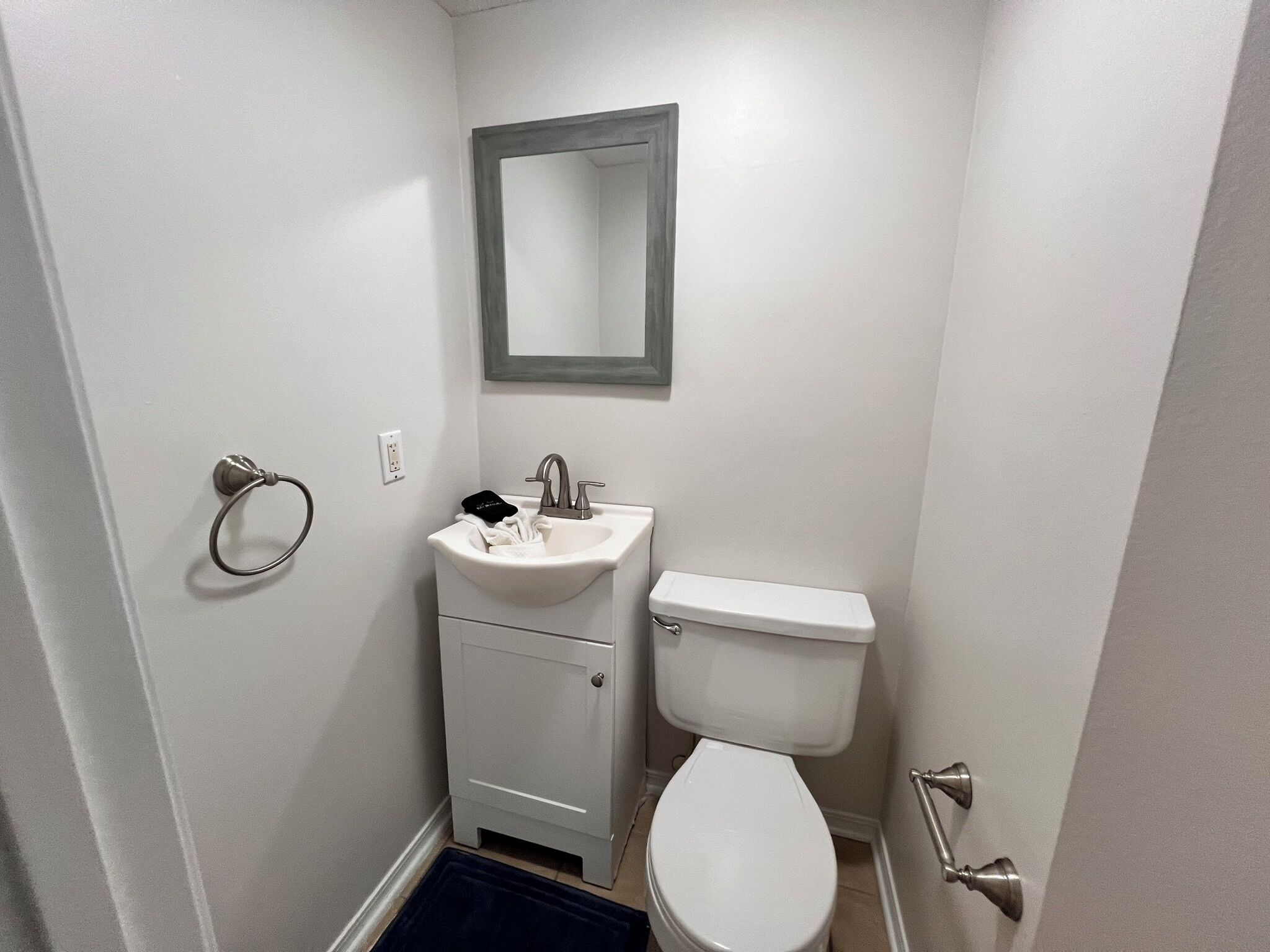 A small, white bathroom with a sink, mirror, and toilet.