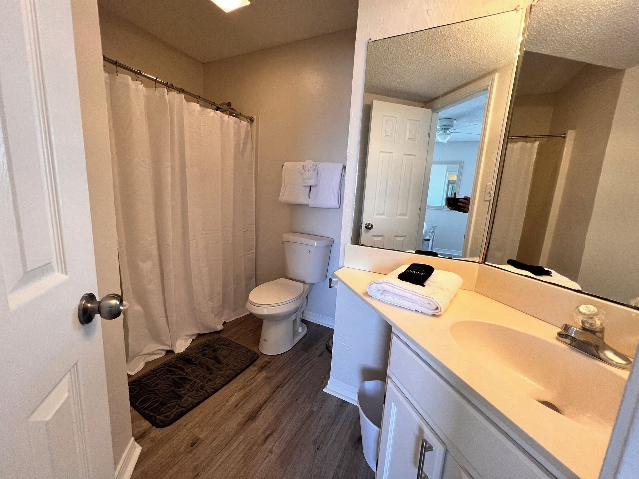 A bathroom with a toilet, a sink, a mirror, and a shower curtain.