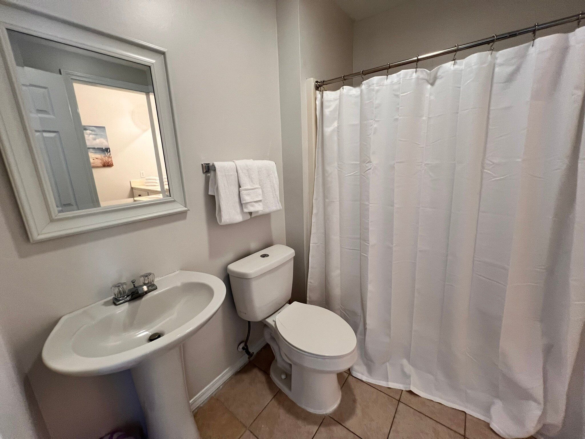A bathroom with a sink, toilet, and shower curtain.