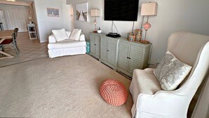 A living room with a sofa, a coffee table, a television, and a cabinet. - Surf Side Shores (Gulf Shores)
