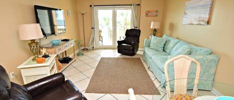 A living room with a sofa, two chairs, a coffee table, and a television.