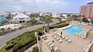 Un complexe hôtelier doté d’une piscine, de chaises longues et offrant une vue sur la plage et l’océan.