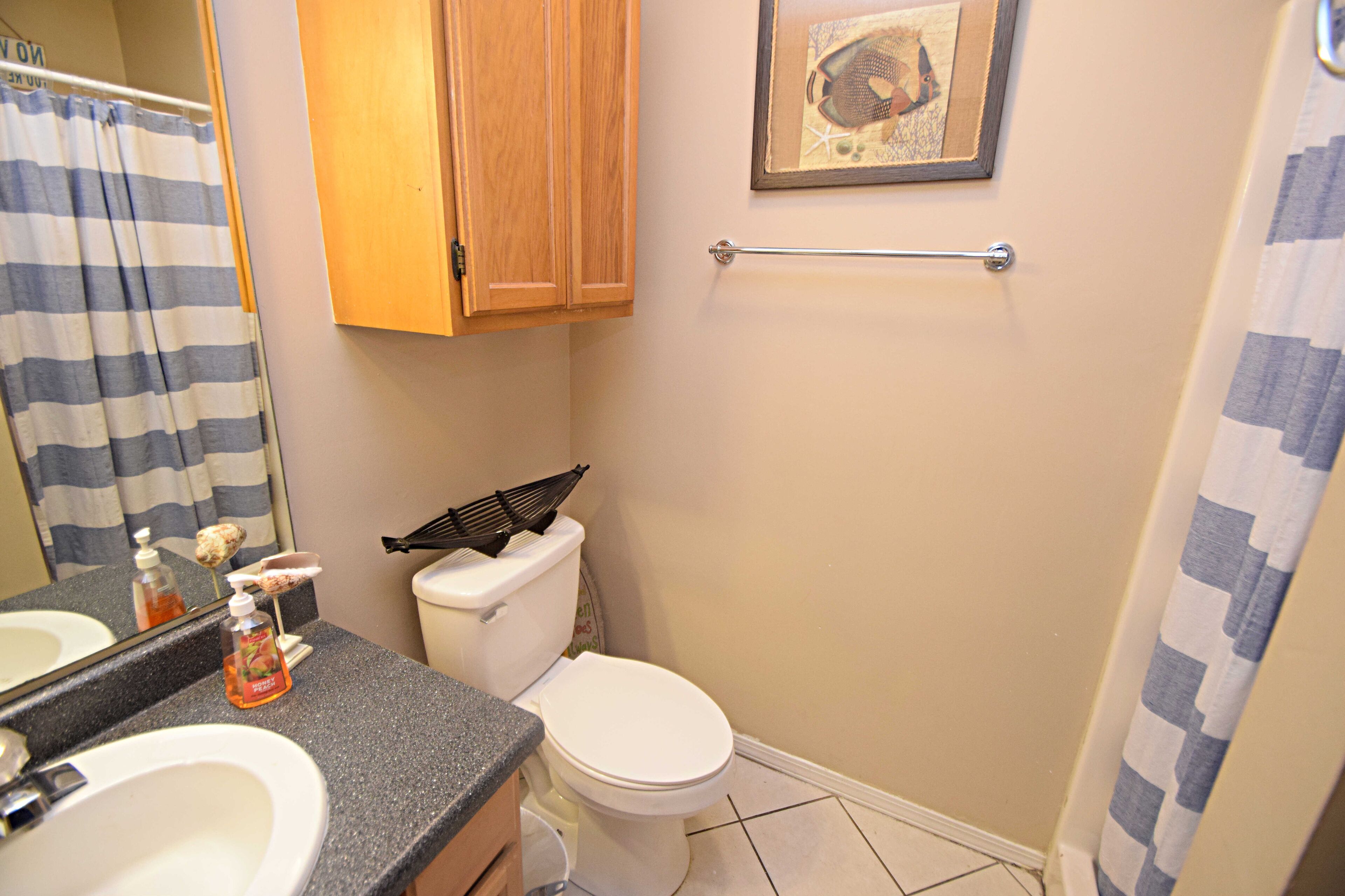 A bathroom with a sink, toilet, and shower curtain.