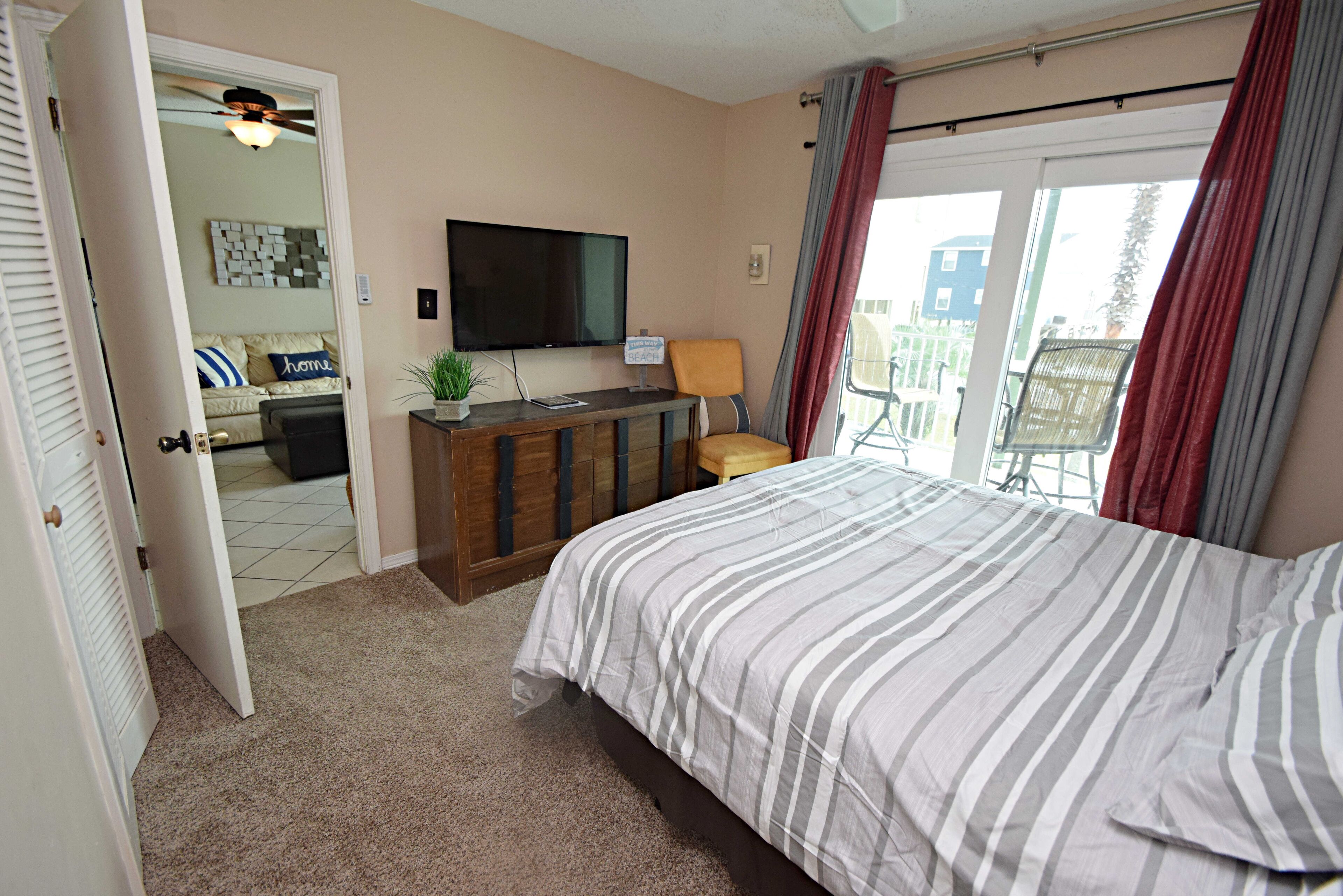 A bedroom with a bed, a TV, a desk, and a chair.