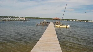 A wooden pier extending into calm water, with a small boat docked at the end. - The Landing (Gulf Shores)