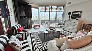 Ein Wohnzimmer mit Kamin, einer Couch, einem Esstisch und Blick auf die Stadt durch große Fenster.