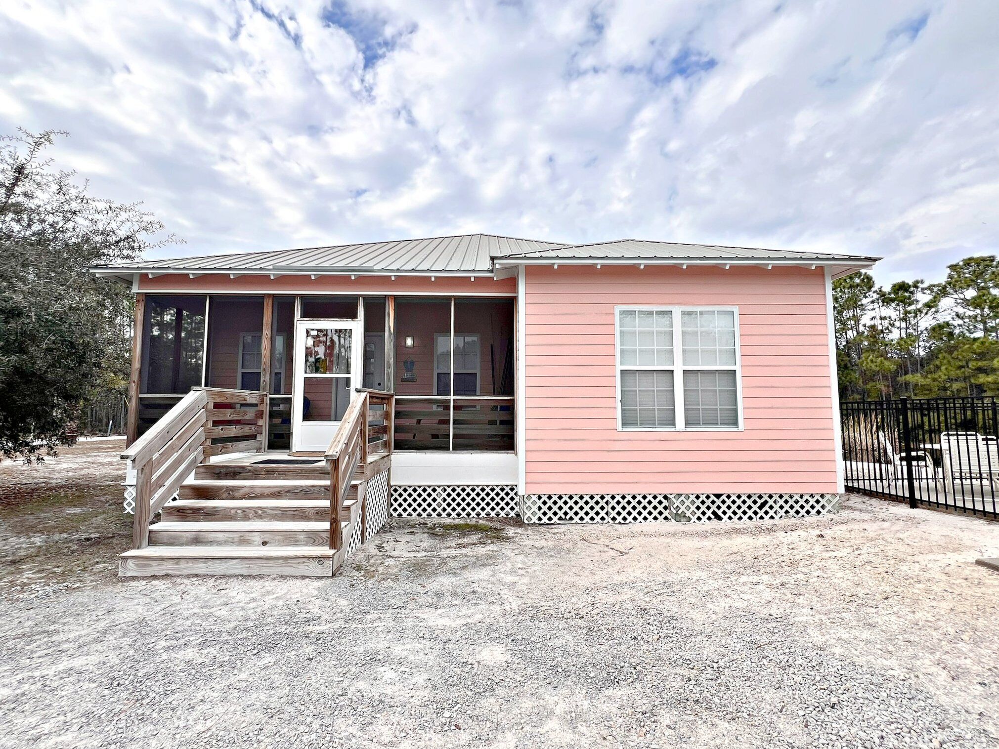 A small pink building with a porch and a staircase leading to the entrance.