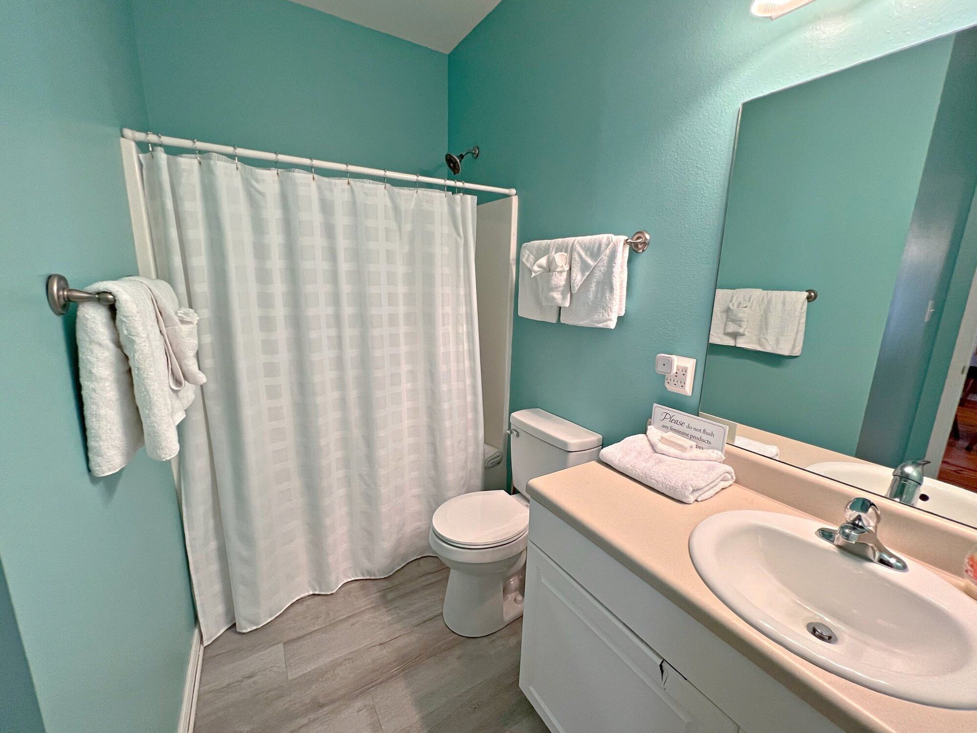 Un baño con cortina de ducha, inodoro, lavabo y barra para toallas.