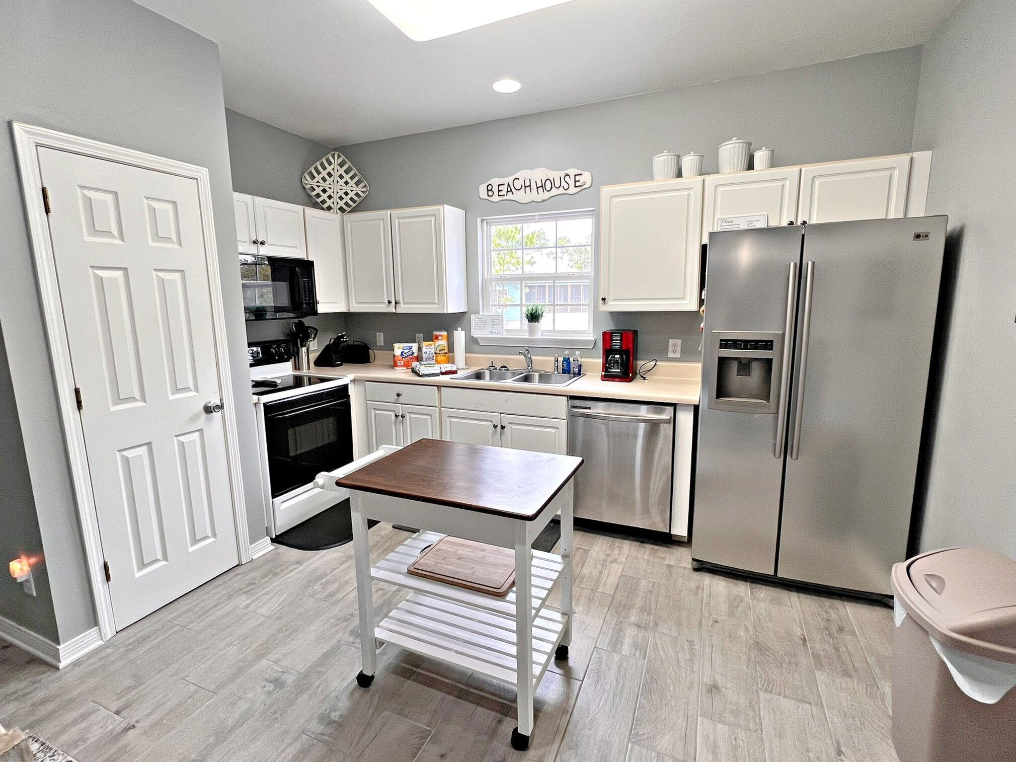 A modern kitchen with white cabinetry, a stainless steel refrigerator, a built-in oven, and a coffee maker.