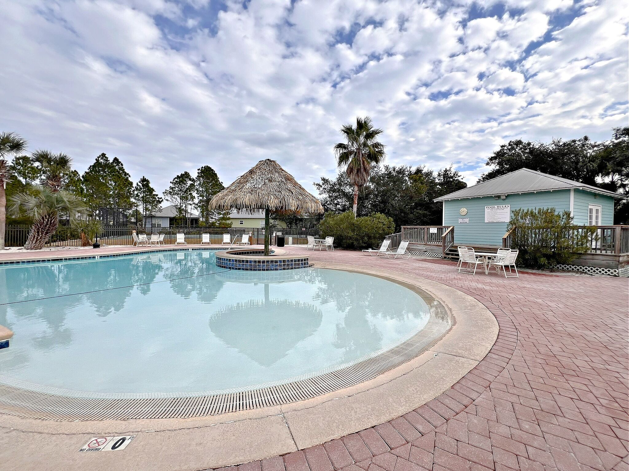 A swimming pool with lounge chairs and a thatched-roof structure.