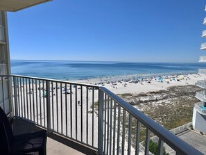 A balcony with a view of a beach with umbrellas and people. - The Whaler (Gulf Shores)