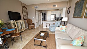 A living room with a sofa, coffee table, TV, and dining area. - Tidewater (Orange Beach)