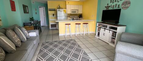 A compact living space with a kitchenette, a sofa, a TV, and a patterned rug.