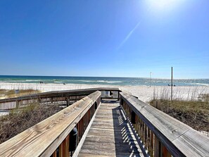 A wooden boardwalk leading to a beach with clear skies and ocean views. - Tradewinds (Orange Beach)