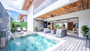 A modern outdoor pool area with a wooden deck, lounge chairs, and a built-in seating area. - Brand New 7 Bedroom Luxury Villa Prime Location on the South End of Jaco Beach (Jaco)
