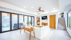 A spacious living area with a white sofa, wooden coffee table, and a ceiling fan. - Brand New 7 Bedroom Luxury Villa Prime Location on the South End of Jaco Beach (Jaco)