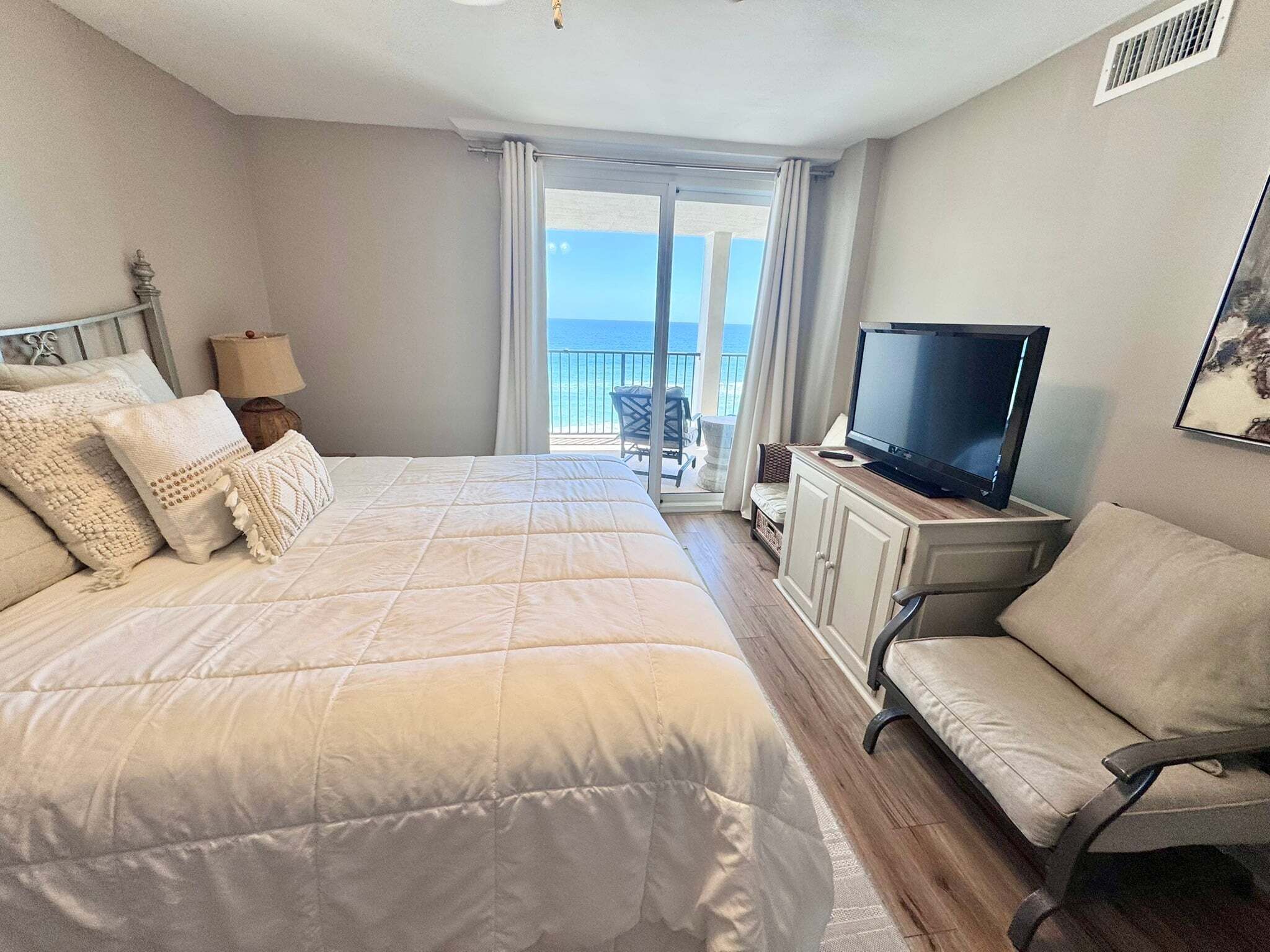 A bedroom with a large bed, a television, and a view of the sea.