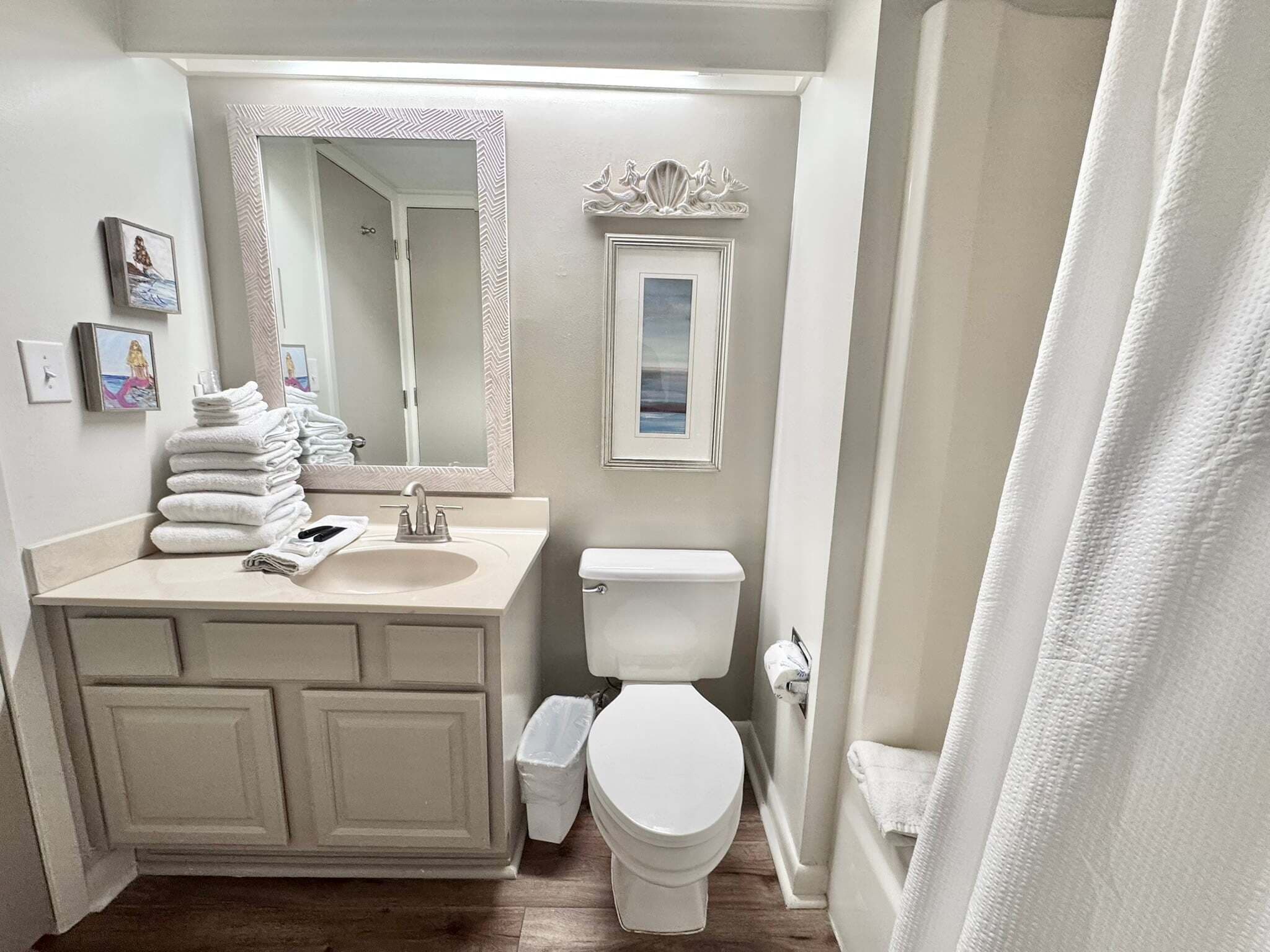 A bathroom with a vanity, sink, mirror, toilet, and a shower curtain.