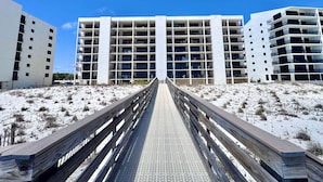 Een hotel aan het strand met een centrale looppad die naar een gebouw met meerdere balkons leidt.