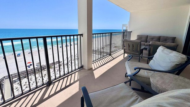 Een balkon met uitzicht op het strand en de oceaan, voorzien van stoelen en een tafel.