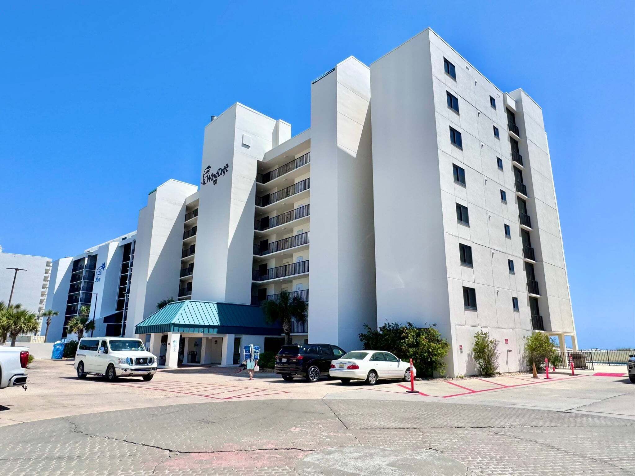 Un hôtel à plusieurs étages, reconnaissable à son grand panneau « WindDrift », doté d’une entrée couverte et d’un parking où sont stationnés plusieurs véhicules.