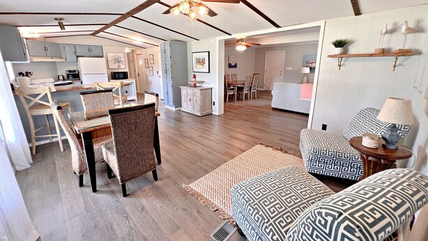 A spacious living area with a dining table, chairs, a sofa, and a ceiling fan. - Oakridge Cottage (Orange Beach)