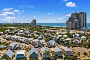 A coastal residential area with houses, a beachfront, and high-rise buildings in the background. - White Sands at Parks Edge (Orange Beach)