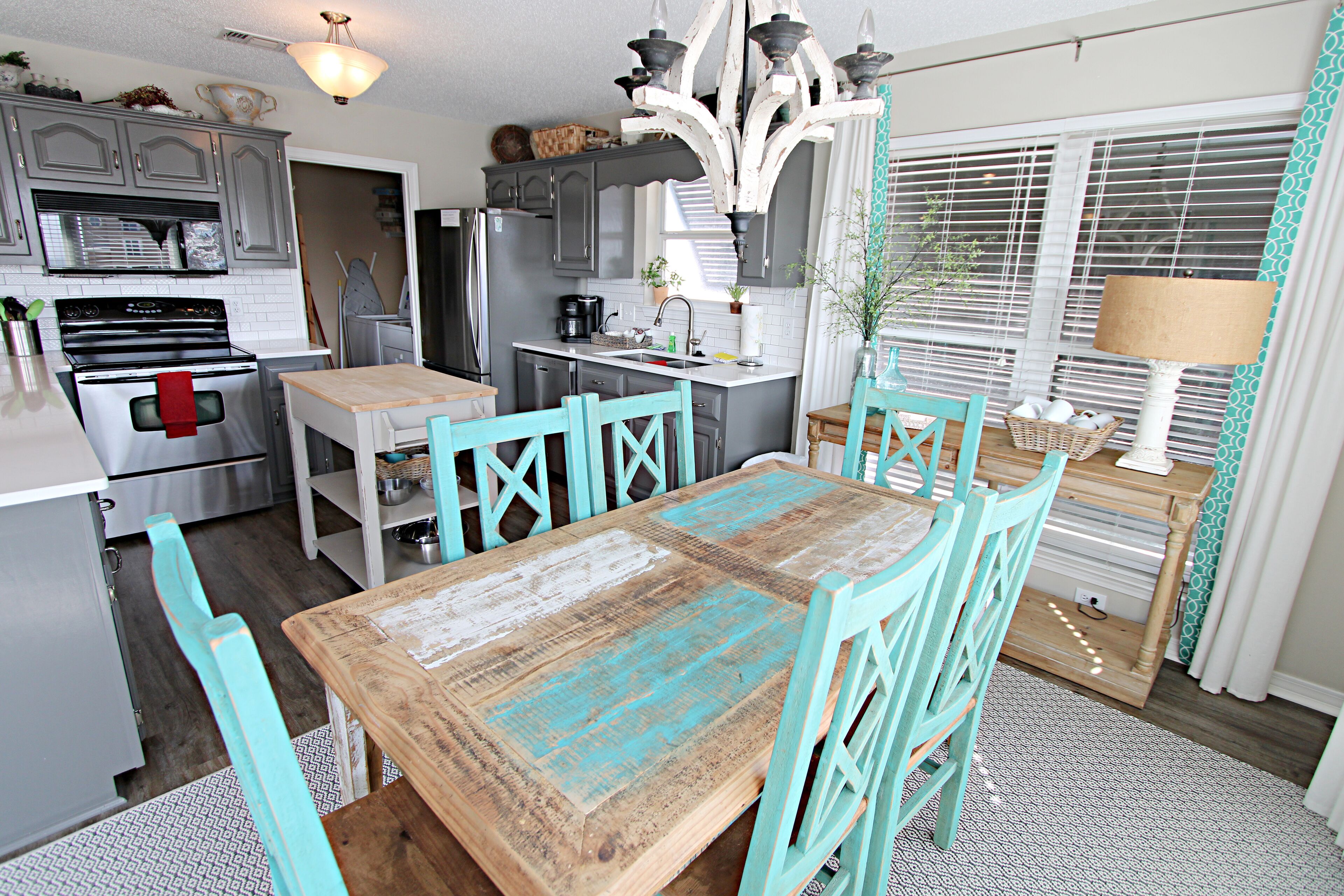 A kitchen with a wooden table and turquoise chairs, a refrigerator, and a stove.