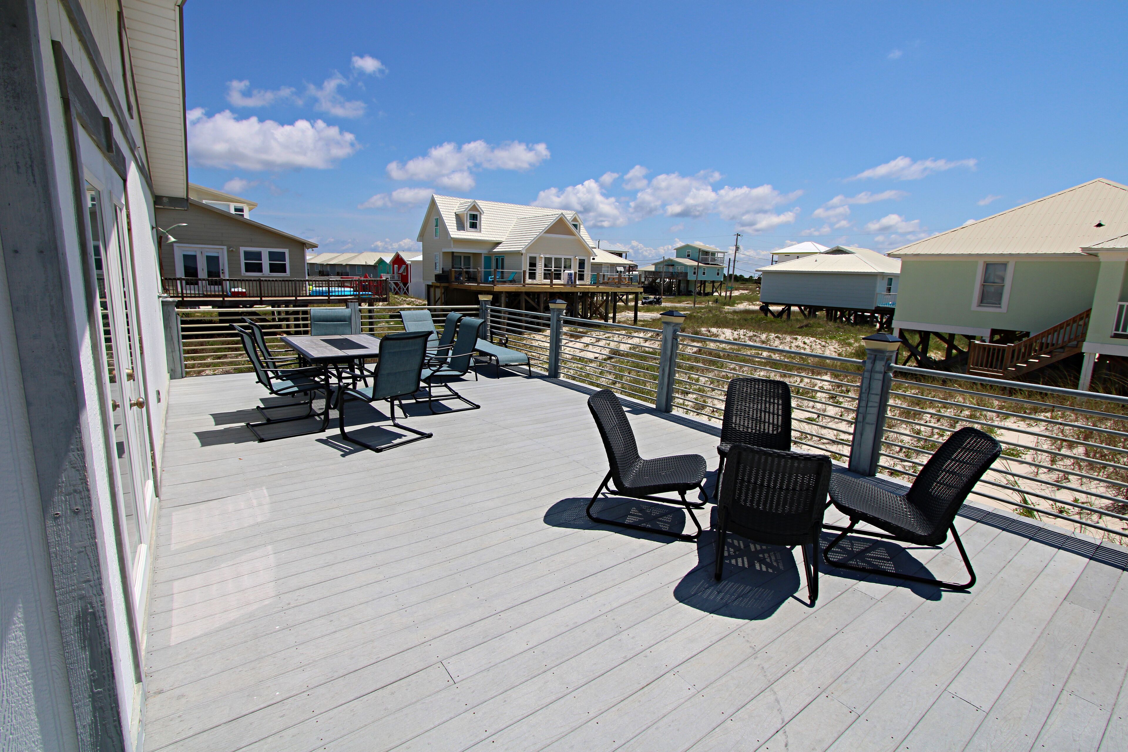A deck with outdoor furniture and a view of beach houses.