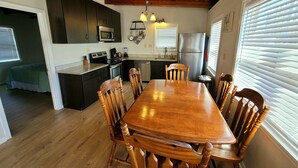 Une cuisine avec des meubles de rangement en bois, une table à manger et des chaises.