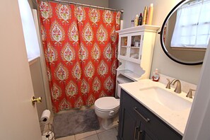 Une salle de bain équipée de toilettes, d’un lavabo et d’un rideau de douche.