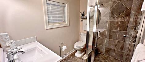 Une salle de bain équipée d’une baignoire, de toilettes et d’une cabine de douche en verre.