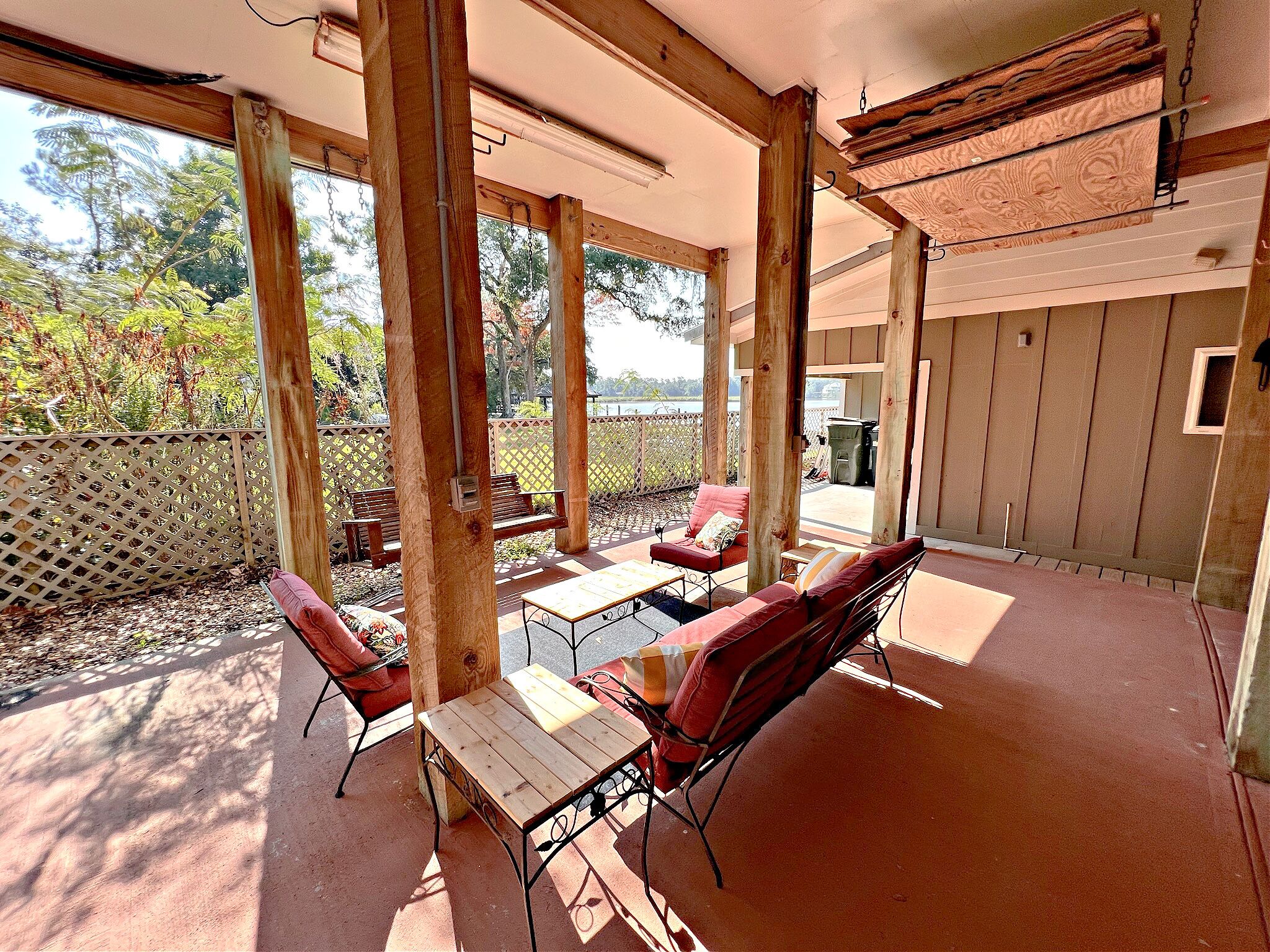 Eine Terrasse im Freien mit Holzmöbeln, einem Tisch und Blick ins Grüne.