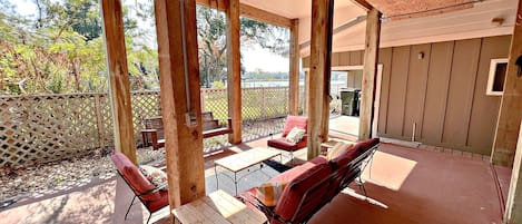 Eine Terrasse im Freien mit Holzmöbeln, einem Tisch und Blick ins Grüne.