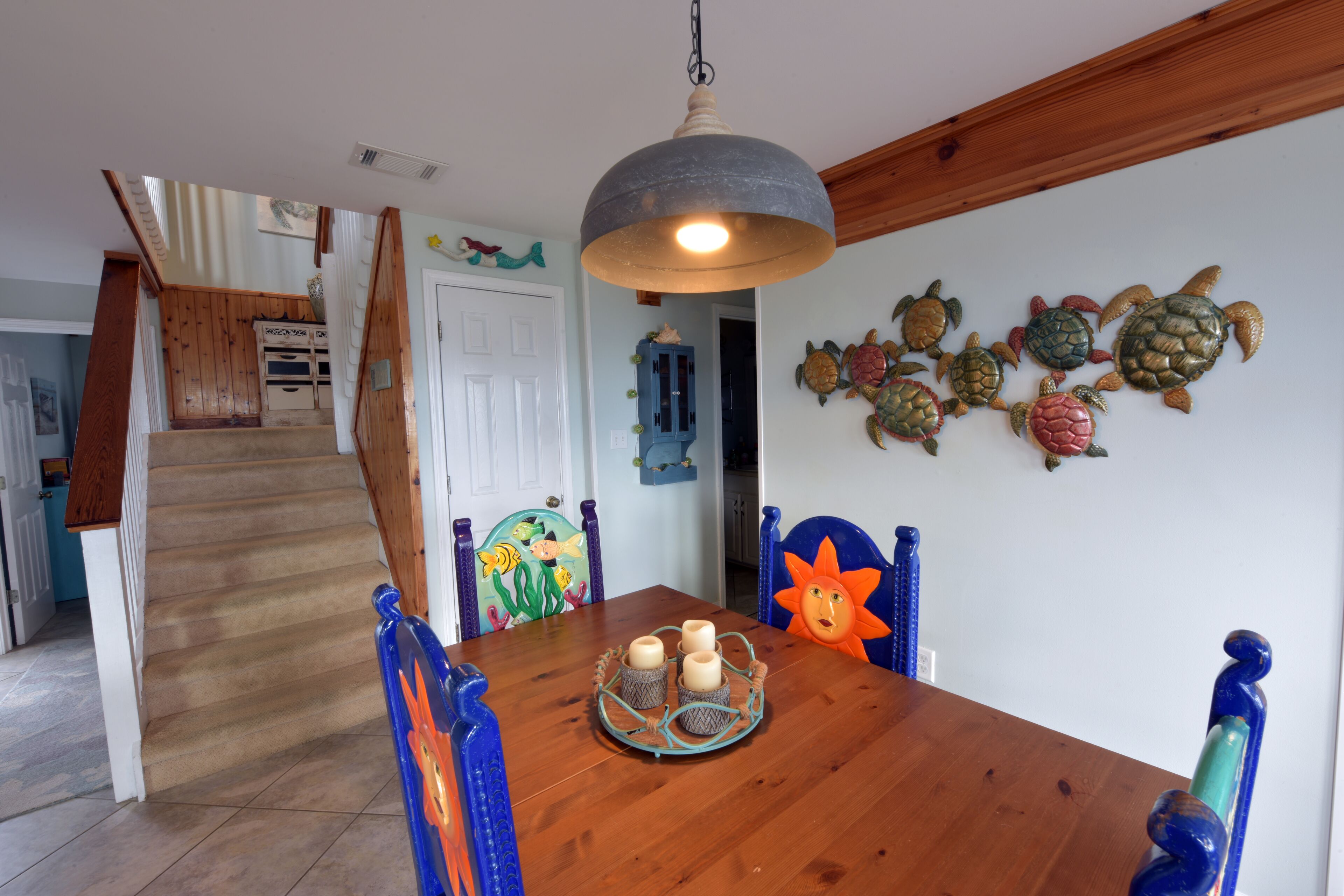 A dining area with a wooden table, blue chairs, and a hanging light fixture.