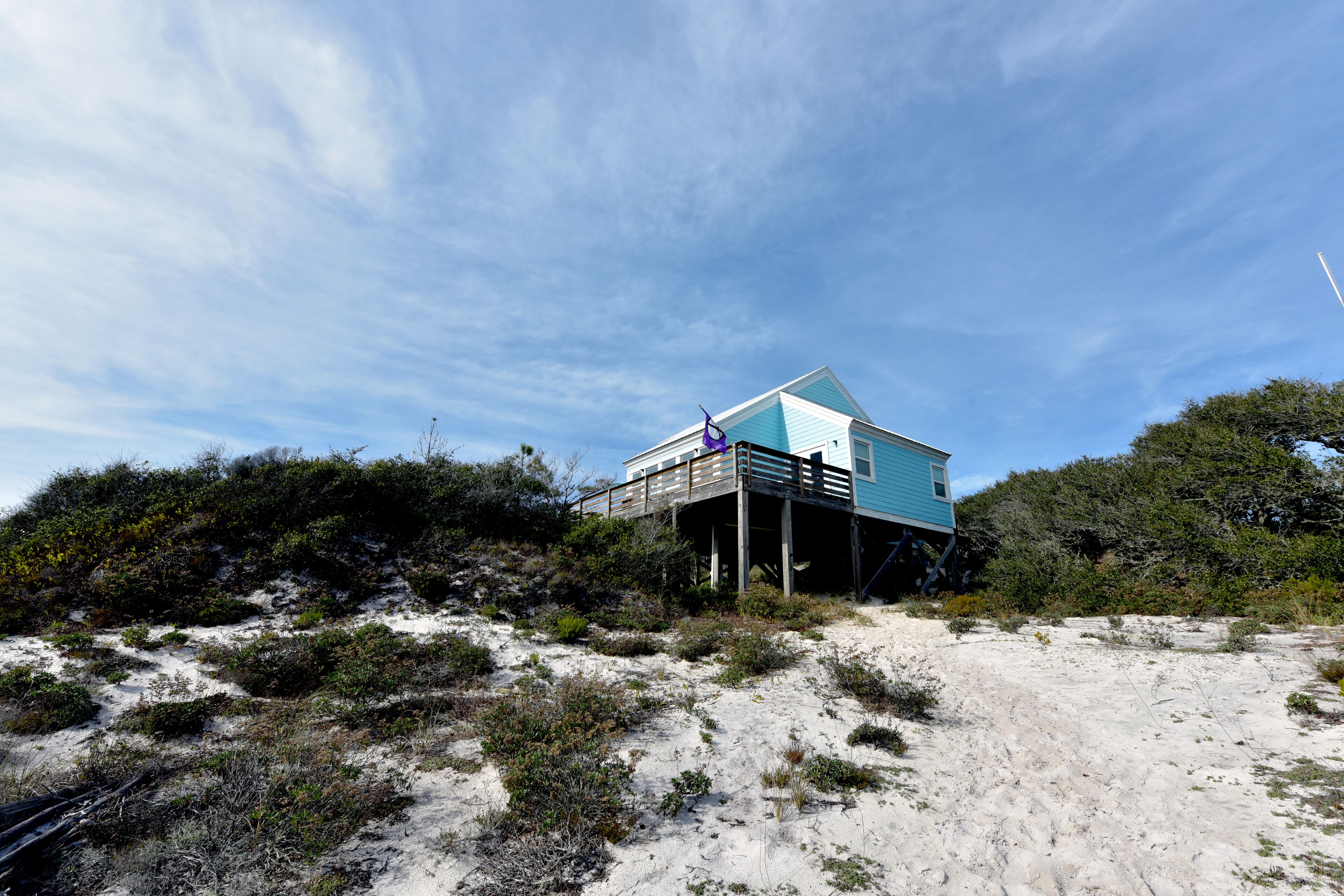 A beachfront house with a wooden deck and a blue exterior.