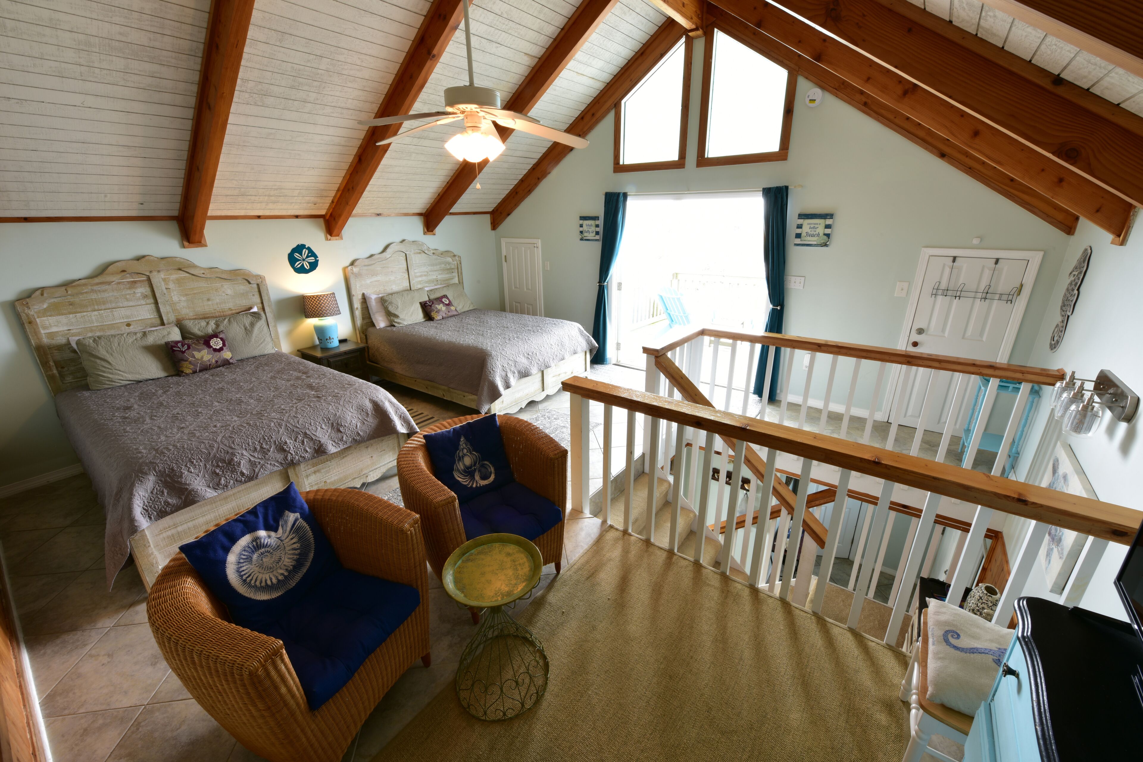 Un dormitorio con dos camas, techo de madera, balcón y escalera.