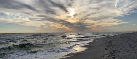 Une plage avec des vagues et un ciel nuageux.