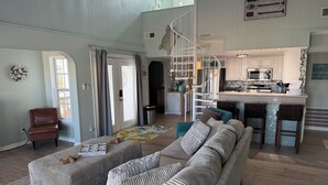 Ein geräumiger Wohnbereich mit einer großen Couch, Hocker und einem Essbereich mit Bar.
