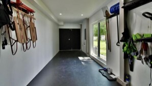 A hallway with climbing equipment on the walls, a black door at the end, and a window with a view of greenery. - Spectacular Waterfront Home  (Orono)