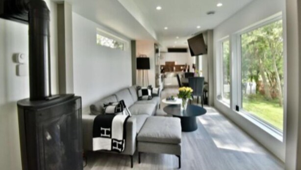 A modern living room with a fireplace, a sofa, a coffee table, and a TV. - Spectacular Waterfront Home  (Orono)