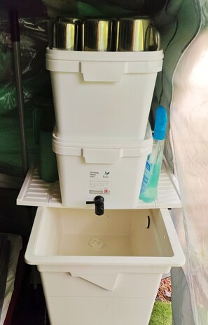 Un dispensador de agua blanco con un filtro, una botella de líquido azul y un lavamanos blanco.