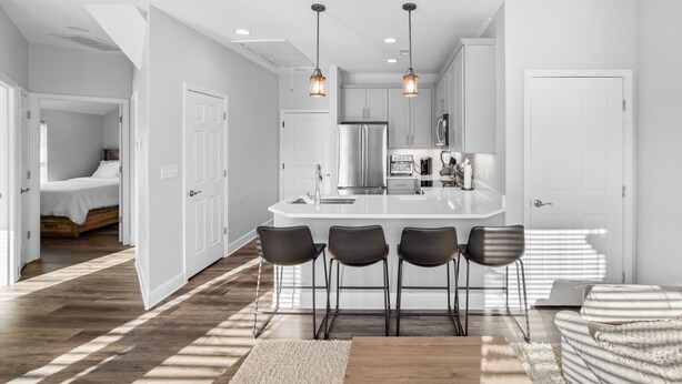 Una cocina moderna con una isla central, taburetes de bar e iluminación colgante.