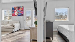 Un dormitorio moderno con cama, sofá, escritorio y televisor.
