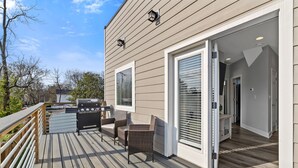 Una terraza con mobiliario exterior y una parrilla, un patio cubierto y vistas del paisaje circundante.
